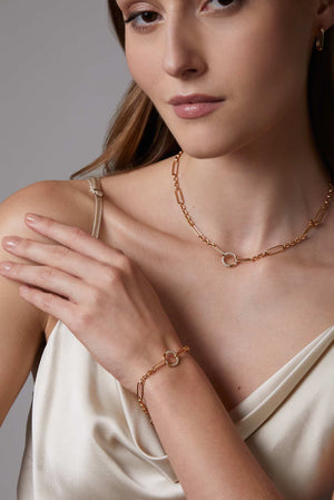 Woman wearing a gold medium size oval hoop earrings on a neutral background