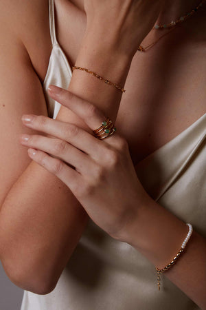 Close-up of a person's arm with jewelry including a bracelet, ring, and necklace.