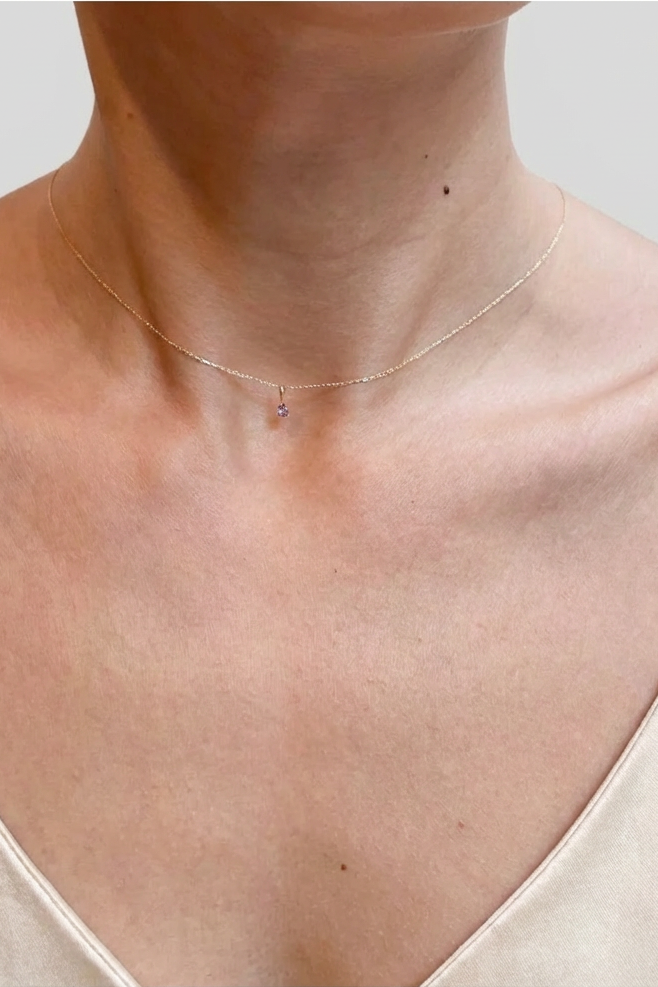 Necklace on a person wearing a beige top against a neutral background