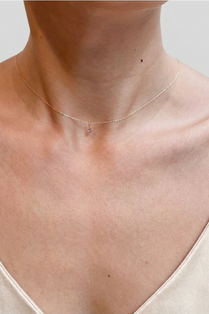 Necklace on a person wearing a beige top against a neutral background