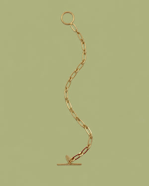 18K gold plated paper clip bracelet with a toggle lock on olive green background