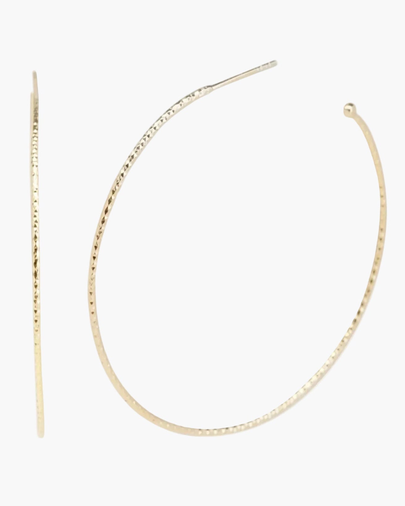 Close-up of a woman wearing large gold hoop earrings and a necklace with a tag pendant.