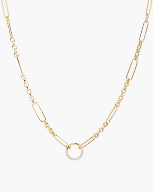 Gold necklace with a small circular pendant on a light gray background