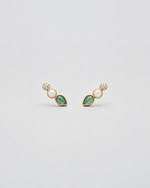A pair of gold-plated drop earrings featuring a marquise-cut green stone, a round white pearl, and a small clear round-cut gemstone, displayed on a clean light gray background.