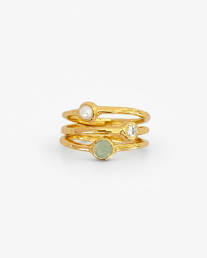 Set of gold rings with embedded stones on a light grey background