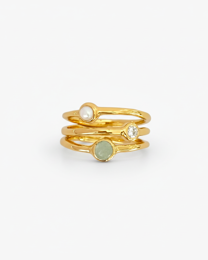 Set of gold rings with embedded stones on a light grey background