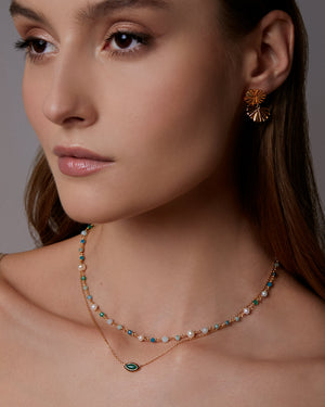 Woman wearing a necklace and earrings with a neutral background