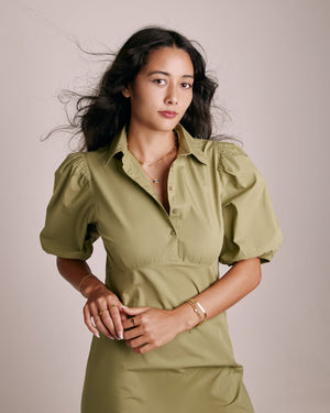 woman in green dress wearing layered gold necklaces