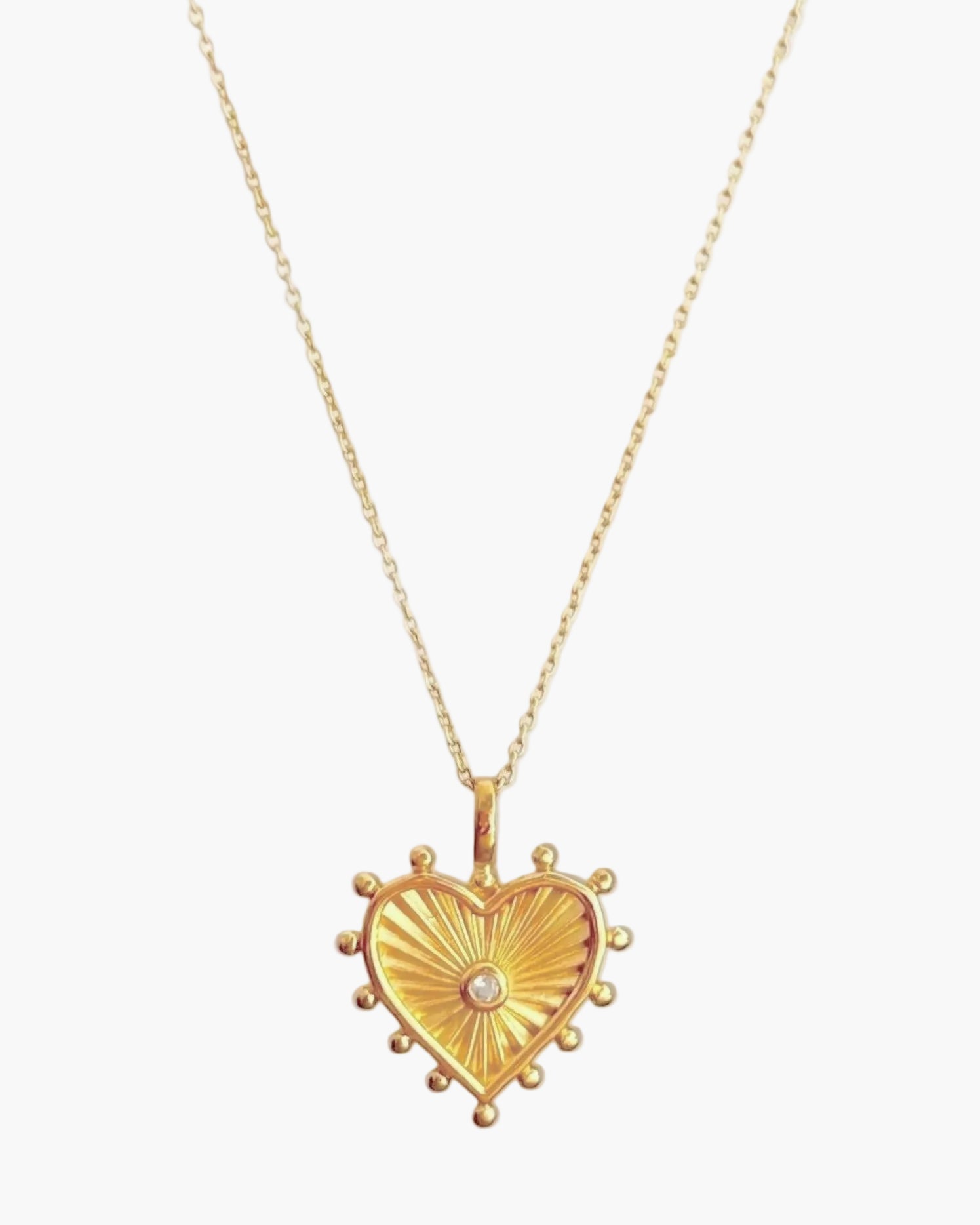 Gold heart-shaped pendant necklace on a light grey background
