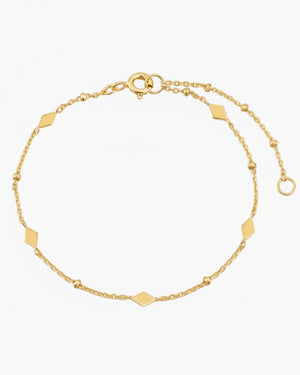 Gold bracelet with geometric accents on a light gray background