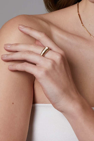 Close-up of a hand wearing a gold ring on a neutral background