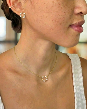 Close-up of a person wearing a gold necklace and earring with a blurred background