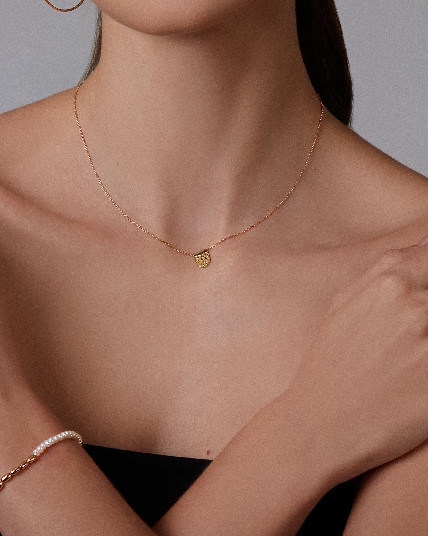 A gold-plated hammered charm necklace with a length of 16 inches, displayed against a light grey background.