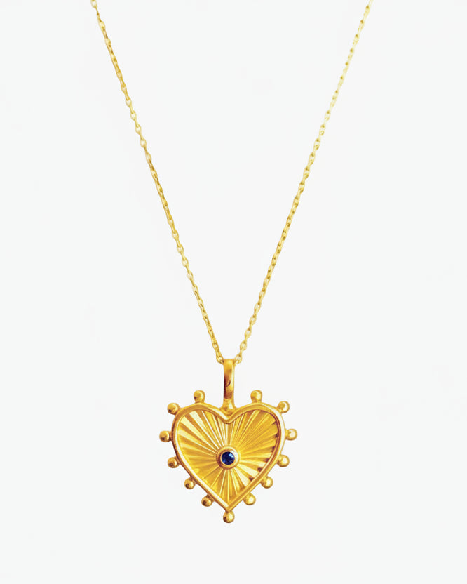 Gold heart-shaped pendant necklace with a blue gemstone on a white background