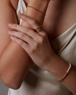 Close-up of a person wearing gold jewelry on a neutral background