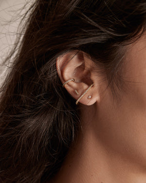 pave bar stud earrings, ear suspender and an ear cuff on a woman's ear. all with cubic zirconia stones