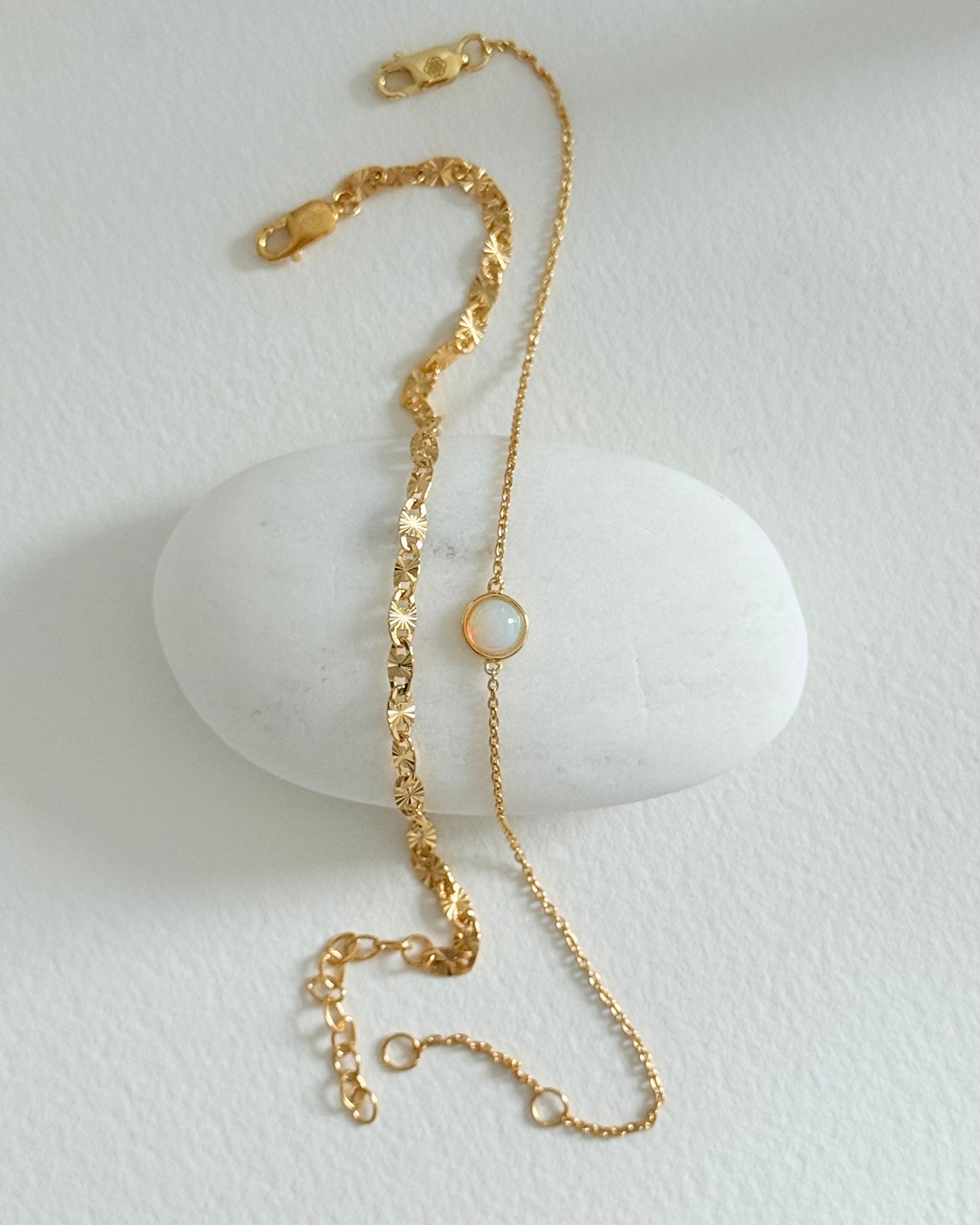 Gold bracelet with a small round charm on a white background