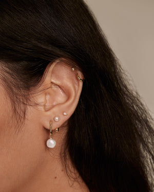 woman mixing earrings with gold plated pearl oval hoop earrings  