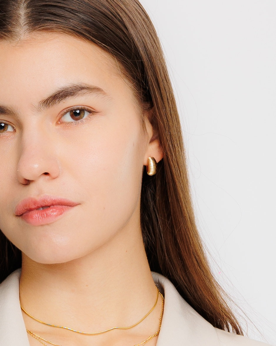 gold ridged dome hoop earrings on a light grey background