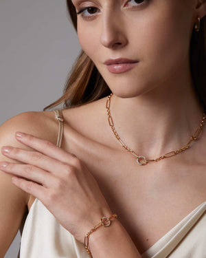 Woman wearing a gold medium size oval hoop earrings on a neutral background