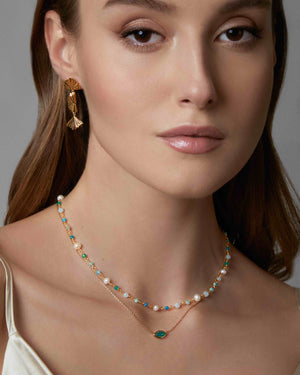 woman wearing layered necklaces including green agate evil eye charm necklace in gold vermeil