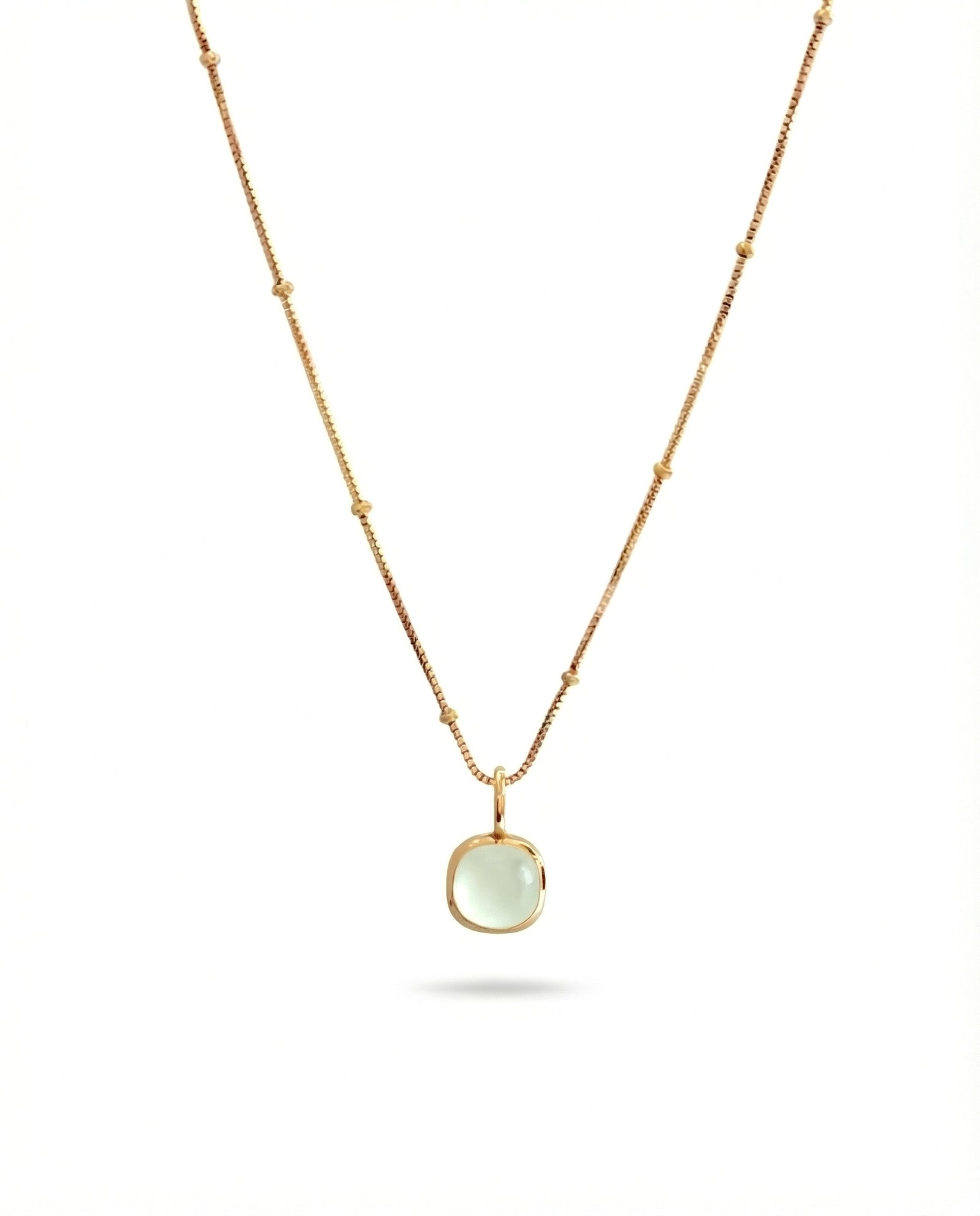 Gold necklace with a green pendant on a white background