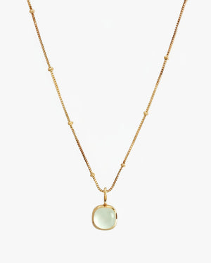 Gold necklace with a green pendant on a white background