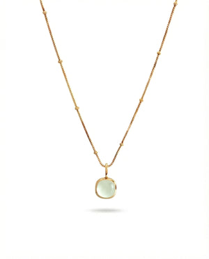 Gold necklace with a green pendant on a white background
