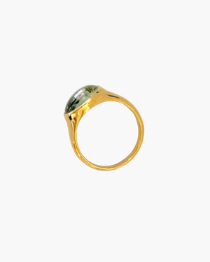 Gold ring with a green cabochon gemstone on a light grey background