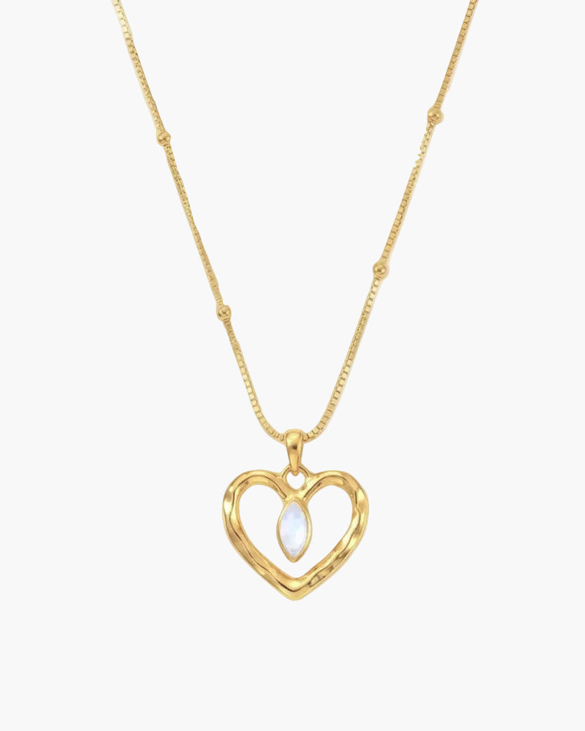 Gold necklace with a heart-shaped pendant on a light grey background