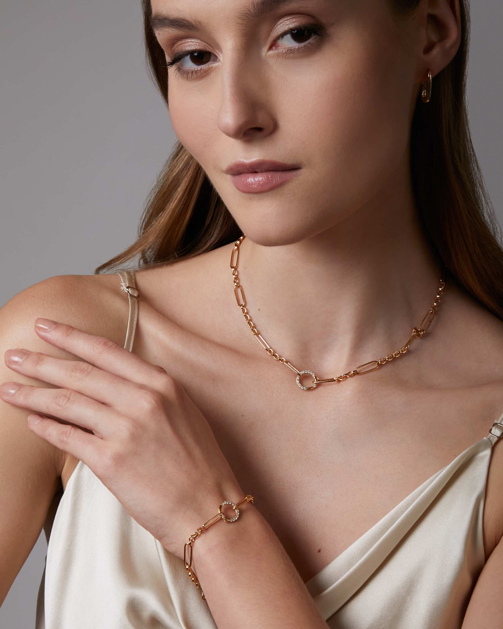 Gold necklace with a small circular pendant on a light gray background