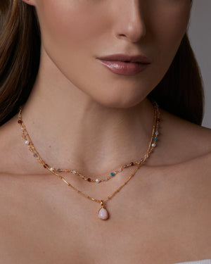 Close-up of a woman wearing a delicate multiple gemstones choker necklace with a grey background