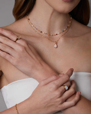 woman wearing 2 necklaces including a choker necklace made from multiple different gemstones