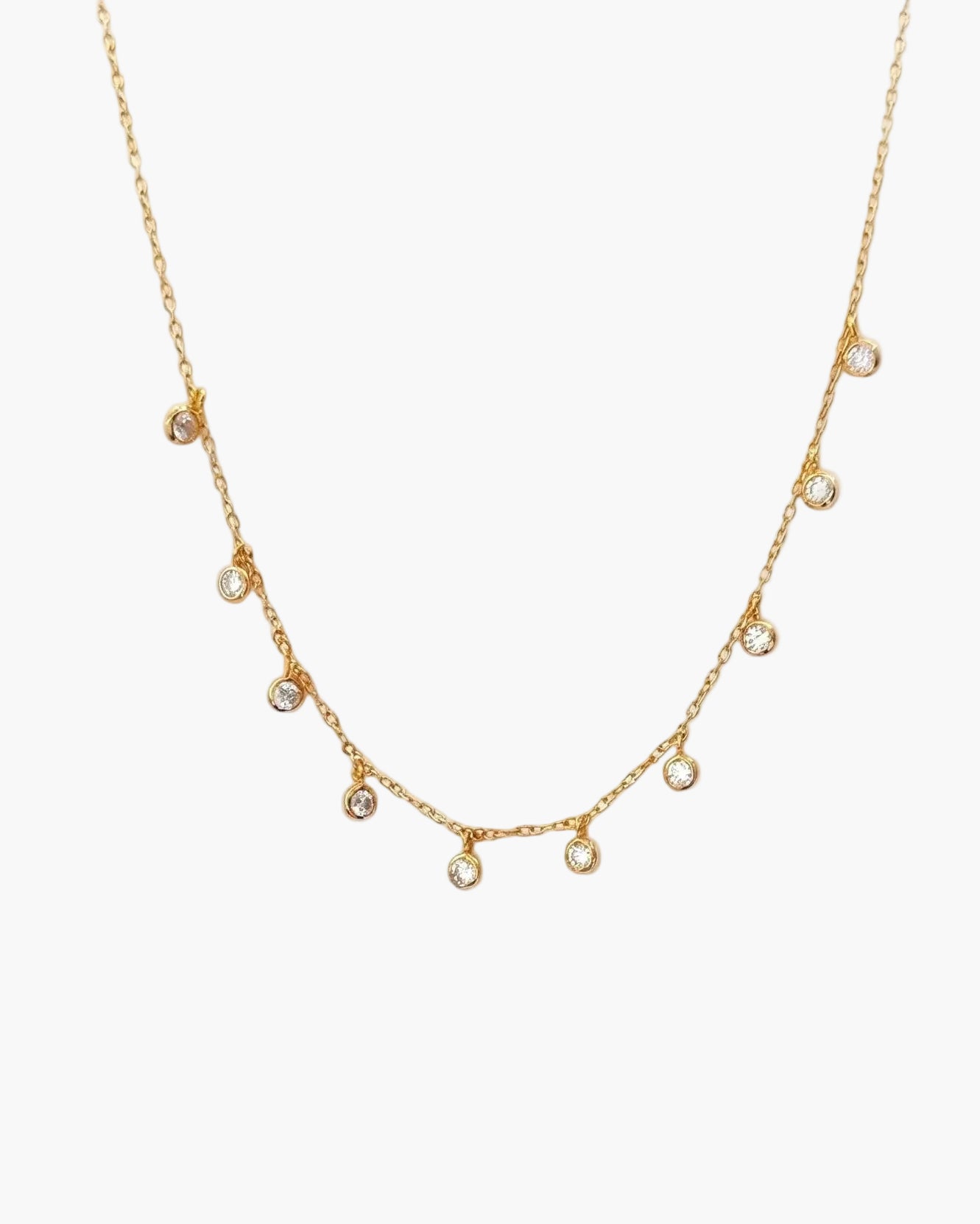 Gold necklace with small cz droplets on a light grey background