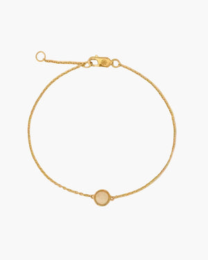 Gold bracelet with a small round charm on a white background
