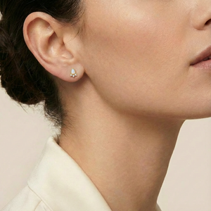 Close-up of a person wearing a delicate earring on a neutral background