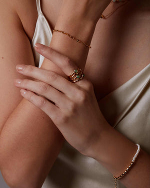 Close-up of a person's arm with jewelry including a bracelet, ring, and necklace.
