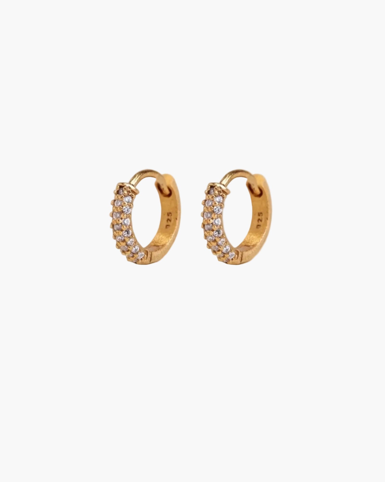 Gold hoop earrings with embedded stones on a beige background