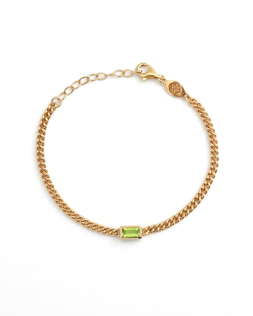 Gold bracelet with a green gemstone on a white background