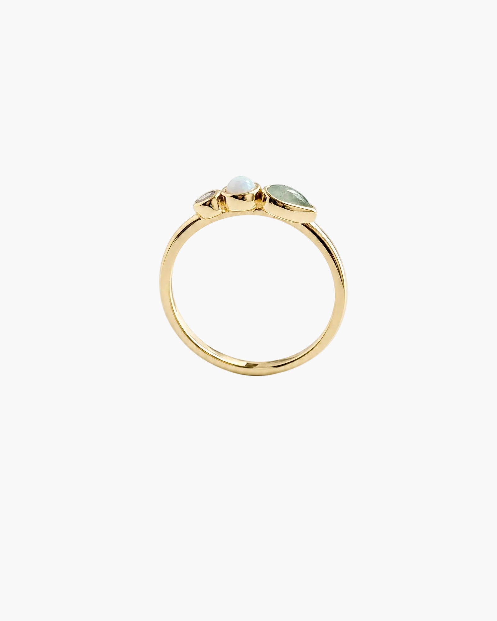 A gold ring with three small light green marquise-cut gemstones clustered at the top, photographed on a clean white background.