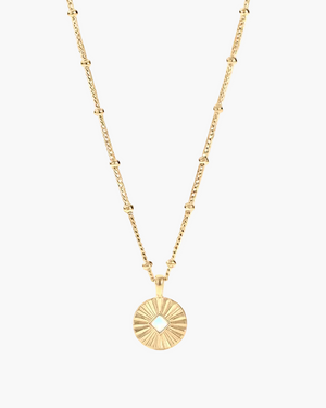 Gold necklace with a sunburst pendant on a white background