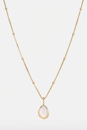 Gold necklace with a teardrop-shaped white moonstone pendant on a light grey background