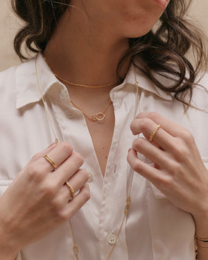 a woman wearing gold twisted eternity rings and other gold layered jewellery