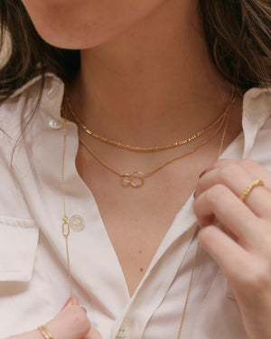woman wearing layered necklaces including gold Figaro chain necklace