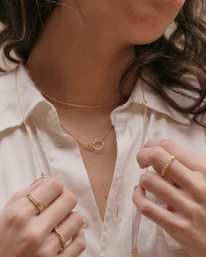 close up of a woman wearing delicate thin ring black spinel and other layered gold jewellery