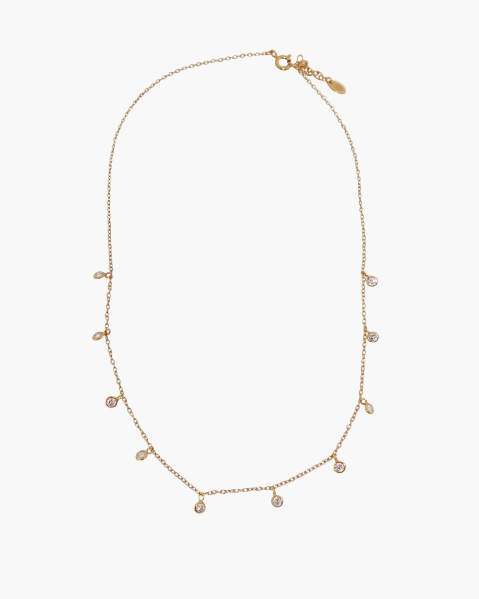 Gold necklace with small cz droplets on a light grey background
