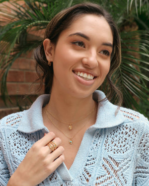 a woman wearing gold flower petal huggie hoop earrings