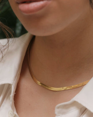 a woman wearing gold herringbone choker