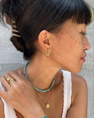 a woman wearing gold hoop earrings 