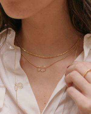 a woman wearing layered gold necklaces including interlocking_double_ring_necklace